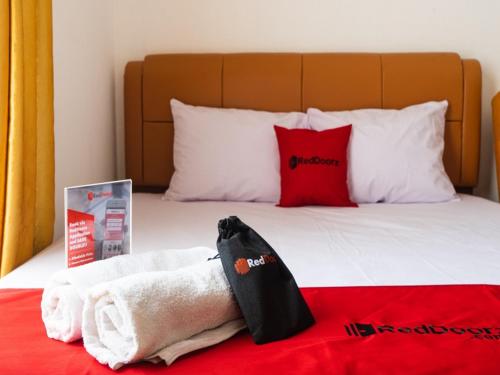 a bed with white towels and red pillows at RedDoorz near Cipinang Indah Mall in Jakarta