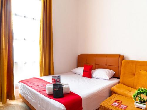 a small bedroom with a bed and a chair at RedDoorz near Cipinang Indah Mall in Jakarta