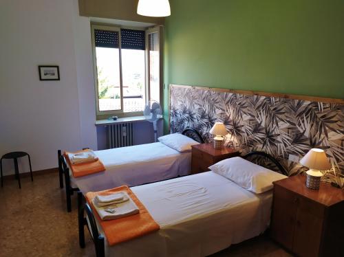 a room with two beds and two tables and a window at Ostello delle cartiere in Toscolano Maderno