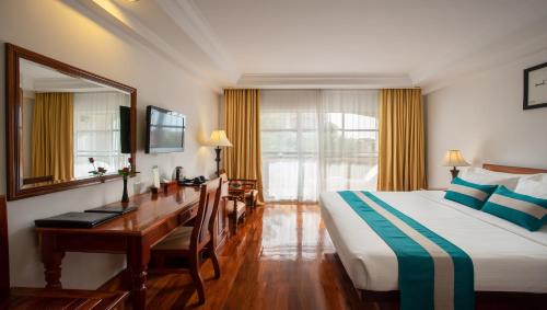 Habitación de hotel con 1 cama, escritorio y 1 dormitorio en Somadevi Angkor Premium, en Siem Reap