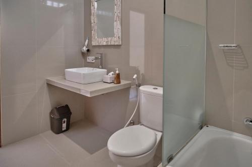 a white bathroom with a toilet and a sink at Gek House Ubud Bali in Ubud