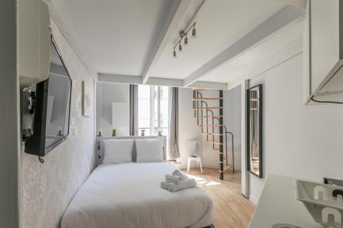 une chambre avec un lit blanc dans une pièce dans l'établissement WS Opéra - Vendôme, à Paris