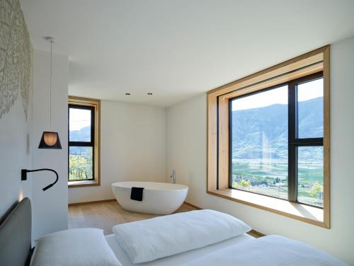1 dormitorio con bañera y ventana grande en Pratenberg Wine Lodge, en Merano