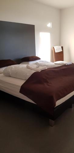 a large bed in a bedroom with a chair at Bifröst Apartments in Bifrost