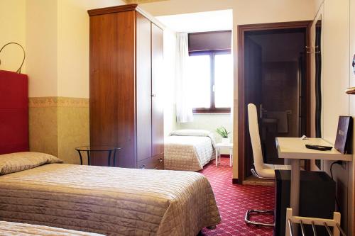 a hotel room with two beds and a desk at Albergo Ristorante Belvedere in Codroipo