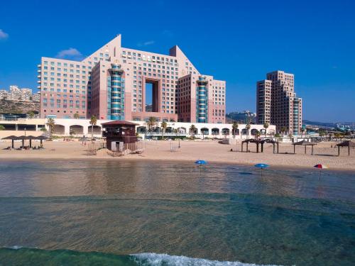 a beach with a large building and some water at Almog Haifa Israel Apartments מגדלי חוף הכרמל in Haifa