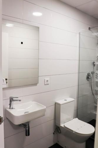 a bathroom with a toilet and a sink and a mirror at R4Hostel in Vigo