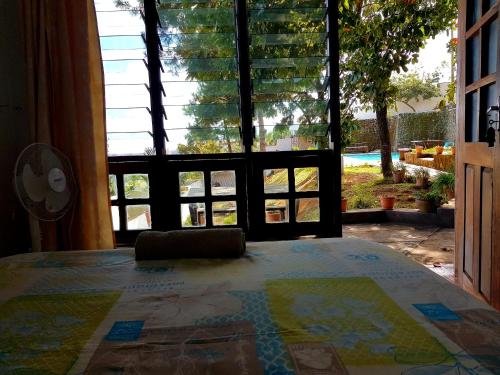 a bedroom with a large window looking out onto a yard at Chinyonga Guesthouse in Limbe