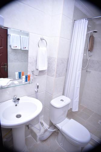 a white bathroom with a toilet and a sink at Urban Point Hotel in Nairobi