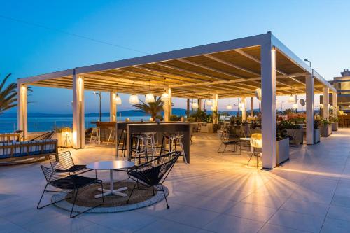 a patio area with chairs, tables and umbrellas at Horizon Blu Boutique Hotel in Kalamata