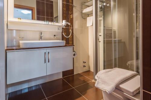 ein Badezimmer mit einem weißen Waschbecken und einer Dusche in der Unterkunft Hotel Koza in Kaş