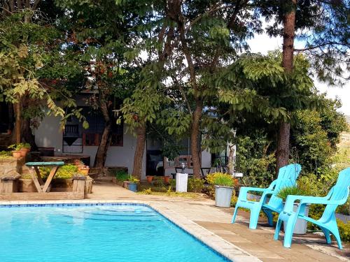 two blue chairs sitting next to a swimming pool at Chinyonga Guesthouse in Limbe