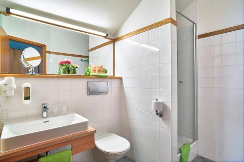 a bathroom with a sink and a toilet and a shower at Hotel An der Brunnader - Die Therme befindet sich 4 Geh-Minuten entfernt in Bad Birnbach
