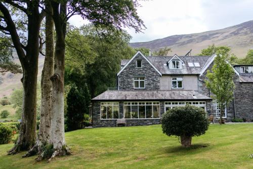 an exterior view of a house with mountains in the background at Borrowdale Gates Hotel in Keswick