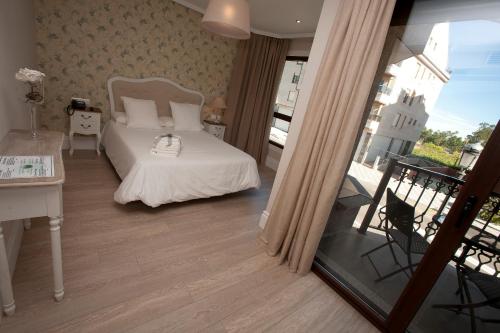 1 dormitorio con 1 cama y balcón en Natura Petit Hotel, en A Revolta