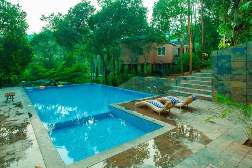 einen Pool mit zwei Liegestühlen neben einem Haus in der Unterkunft Nexstay Lakkidi Village Resort in Vythiri