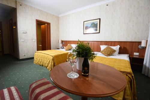 a hotel room with two beds and a table with a wine glass at Hotel Karpos in Skopje