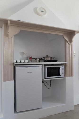 a small kitchen with a microwave and a refrigerator at Chez Georges in Parikia