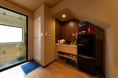 a kitchen with a sink and a refrigerator with a microwave at Shirakabanoyado - SHIOKUSA, 白樺の宿 - 塩草 in Osaka