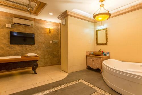 a bathroom with a tub and a tv and a toilet at Minh Tam Hotel and Spa in Ho Chi Minh City