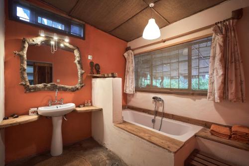 uma casa de banho com um lavatório e uma banheira em Hillside Retreat – Africa Amini Life em Usa River