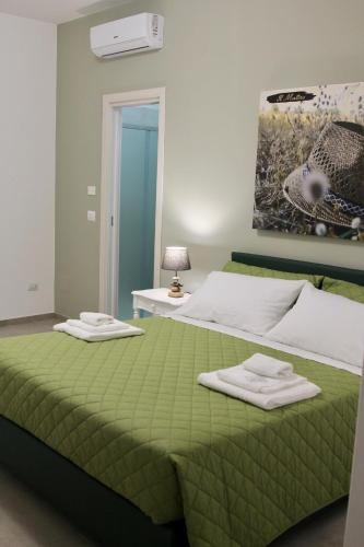 a bedroom with a green bed with towels on it at Il Matino in Leverano