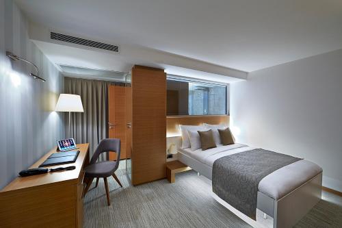 イスタンブールにあるMilport Hotel Levent Istanbulのベッド、デスク、コンピュータが備わるホテルルームです。