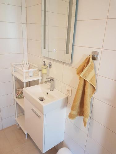 ein weißes Badezimmer mit Waschbecken und Spiegel in der Unterkunft Apartment ALMA - to travel is to live in Celje