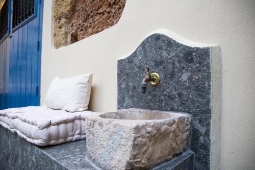 a bathroom with a stone sink and a bench at L' Hôtellerie Easy Suites in Palermo
