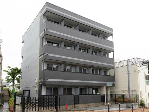 un edificio alto gris con una valla delante en Tabist Gloire Osaka en Osaka
