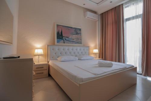 a bedroom with a large white bed with two lamps at Black Sea Riviera Hotel in Shekvetili