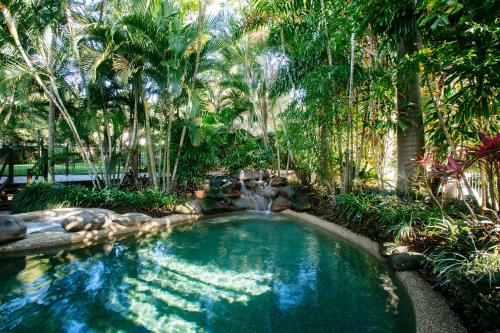 a swimming pool with a waterfall and palm trees at City Oasis Inn Townsville, SureStay Collection by BW in Townsville