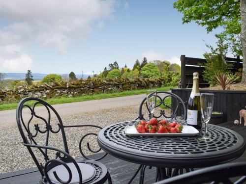 a table with a plate of fruit and a bottle of wine at Rowanlea Lodge With Hot Tub in Marykirk