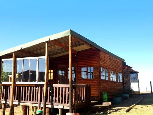 a log cabin with a large porch and windows at Dargle Forest Lodge in Dargle
