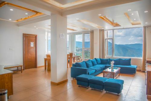a living room with a blue couch and large windows at The White Haven Homestay (Shimla) in Shimla