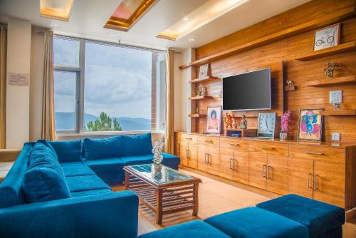 a living room with a blue couch and a tv at The White Haven Homestay (Shimla) in Shimla