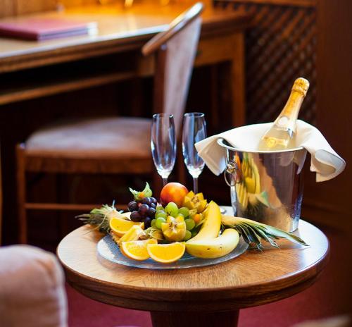 a table with a plate of fruit and wine glasses at Hotel Abácie & Wellness in Valašské Meziříčí