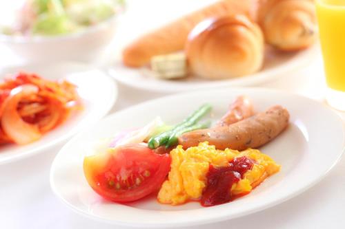 a plate of food with sausage and tomatoes on a table at Hotel Wing International Tomakomai in Tomakomai