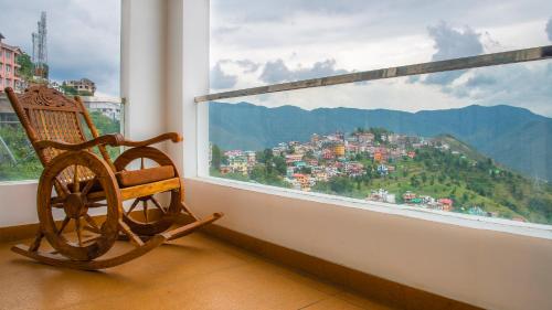 a rocking chair in a room with a large window at The White Haven Homestay (Shimla) in Shimla
