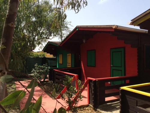 a red house with a green door in a yard at Camping Valle dei Templi in San Leone