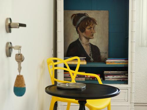 a table and a yellow chair in front of a painting at Bleuvelours in Andernos-les-Bains
