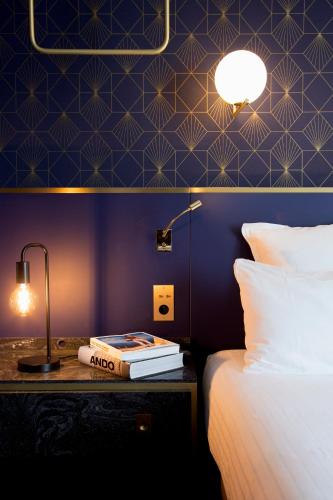 a bedroom with a bed and a table with a lamp at Hôtel Léna in Paris