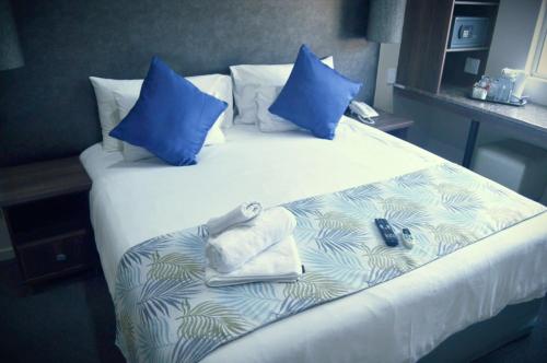 a large bed with blue pillows and towels on it at Essenwood Park Hotel in Durban