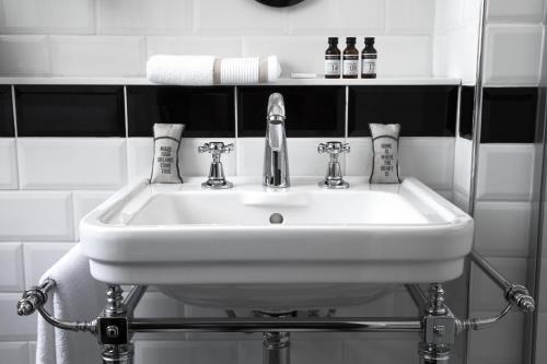 lavabo blanco en el baño con azulejos blancos y negros en Hôtel Léna, en París