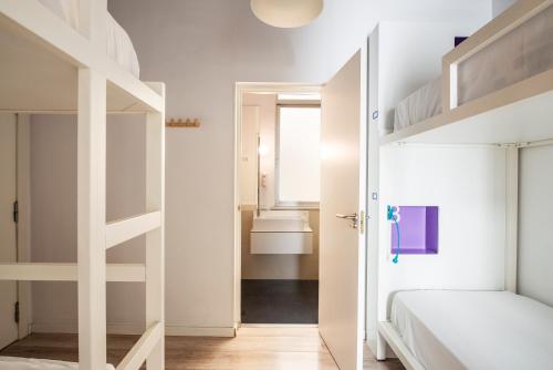 a bedroom with white bunk beds and a hallway at Safestay Madrid Central in Madrid