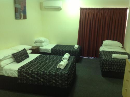a hotel room with three beds and a chair at Parkside Motel Ayr in Ayr