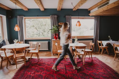 a woman walking through a restaurant with tables and chairs at SEEBICHL haus am see Designhotel Kitzbühel in Kitzbühel