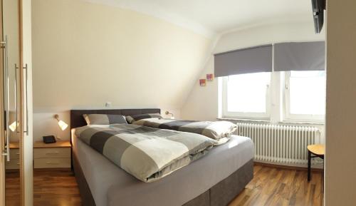een slaapkamer met een groot bed en 2 ramen bij Haus Bramland --- 2 FeWo's --- EG 60qm und OG 55qm in Haselünne