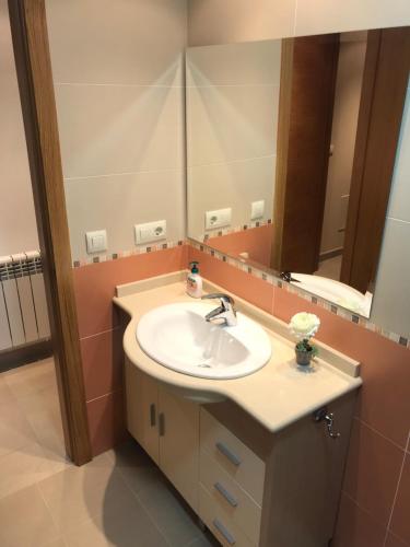 ein Badezimmer mit Waschbecken und Spiegel in der Unterkunft Apartamentos Trebol in Sanxenxo