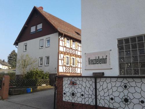 een gebouw met een bord op een hek naast een huis bij Kreuzdellenhof Ferienzimmer in Hembach
